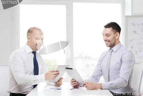 Image of two smiling businessmen with tablet pc in office