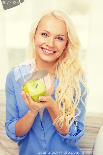 Image of smiling woman with green apple at home