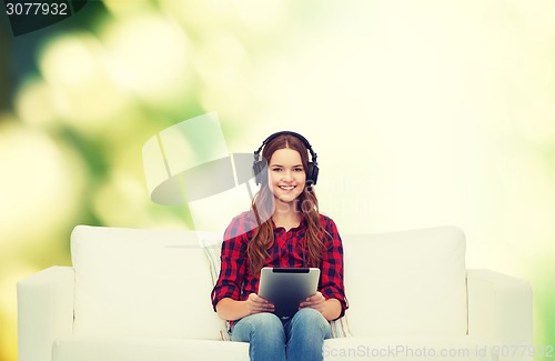 Image of girl sitting on sofa with headphones and tablet pc