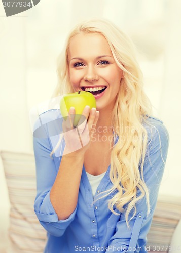 Image of smiling woman with green apple at home