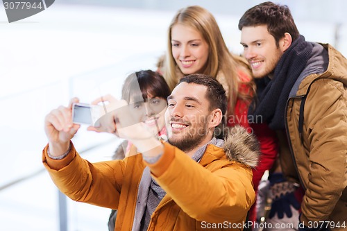 Image of happy friends with camera on skating rink