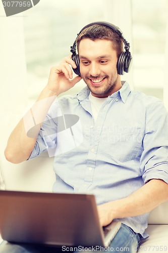 Image of smiling man with laptop and headphones at home