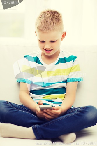 Image of smiling little boy with smartphone at home