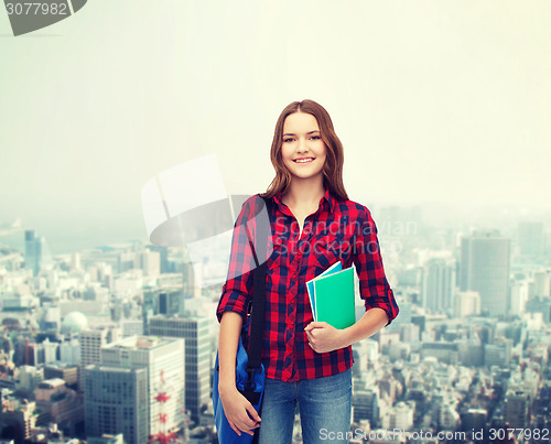 Image of smiling female student with bag and notebooks