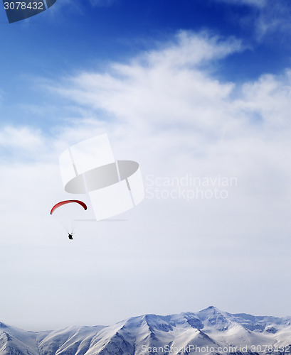 Image of Parachutist silhouette of mountains in windy sky