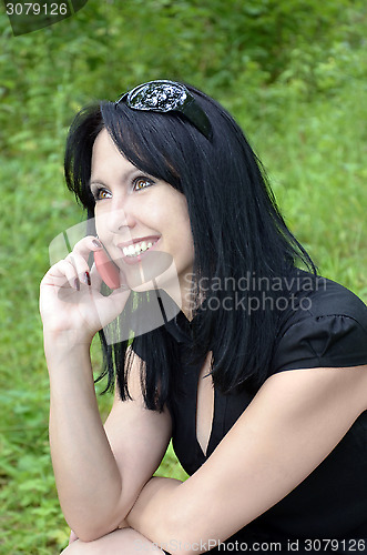 Image of A smiling girl in a black dress with a red phone