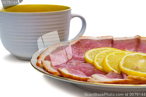 Image of The dish with slices of ham and lemon on a white background.