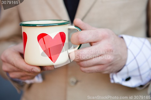 Image of man holding hot cup of coffee