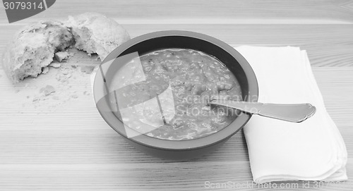 Image of Soup on a table with a torn bread roll