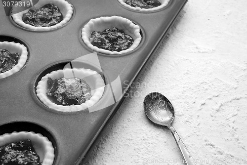 Image of Filled, uncooked jam tarts in a tin