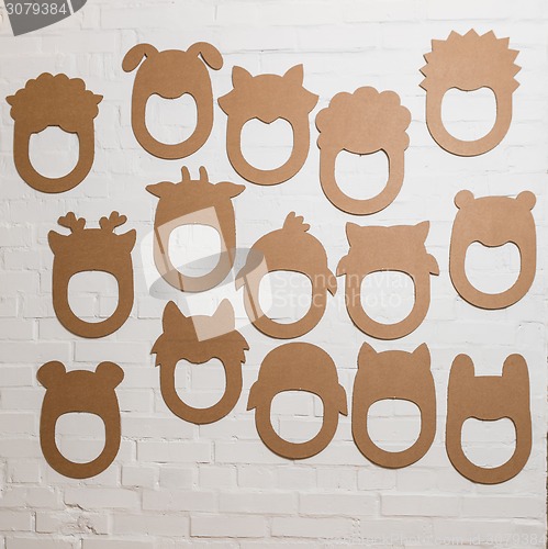 Image of Set of cardboard masks on a white brick wall.