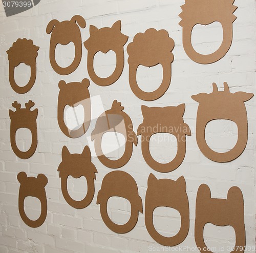 Image of Set of cardboard masks on a white brick wall.