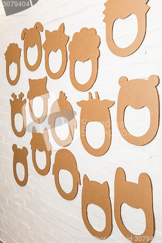 Image of Set of cardboard masks on a white brick wall.