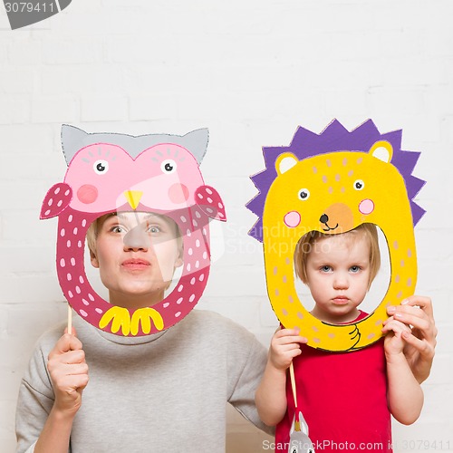 Image of Little girls and mother holding lion mask on white background