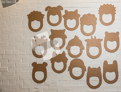 Image of Set of cardboard masks on a white brick wall.