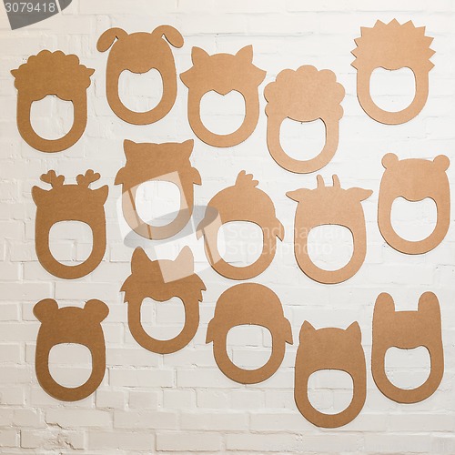 Image of Set of cardboard masks on a white brick wall.