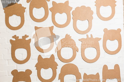 Image of Set of cardboard masks on a white brick wall.