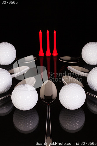 Image of Teaspoons and golf equipments on the black glass table