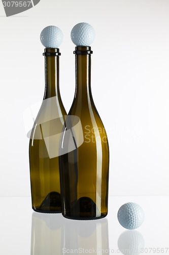 Image of Empty wine bottles and golf balls on a glass desk