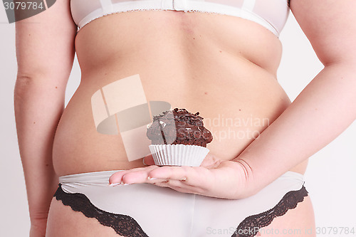 Image of Fat woman holding a muffin behind his back in his hand