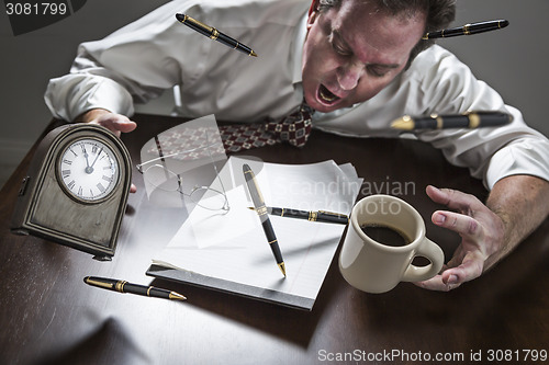 Image of Stressed Man At Desk, Pens, Coffee, Glasses, Clock Flying Up