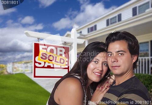 Image of Hispanic Couple, New Home and Sold Real Estate Sign