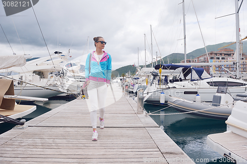 Image of relaxed young woman walking in marina