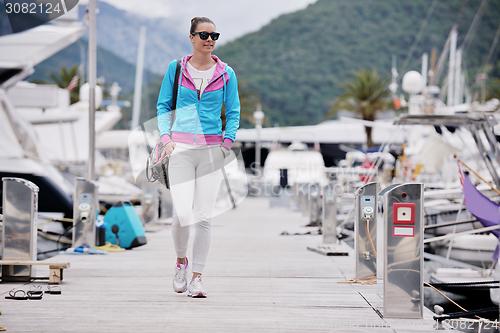 Image of relaxed young woman walking in marina