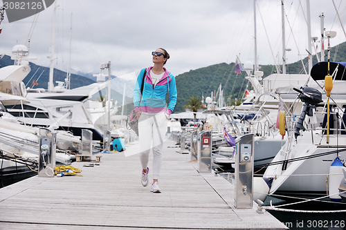 Image of relaxed young woman walking in marina