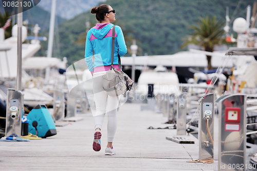 Image of relaxed young woman walking in marina