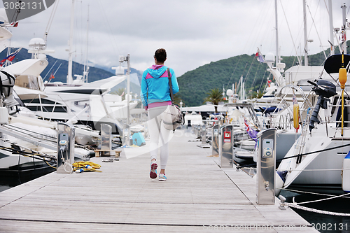 Image of relaxed young woman walking in marina