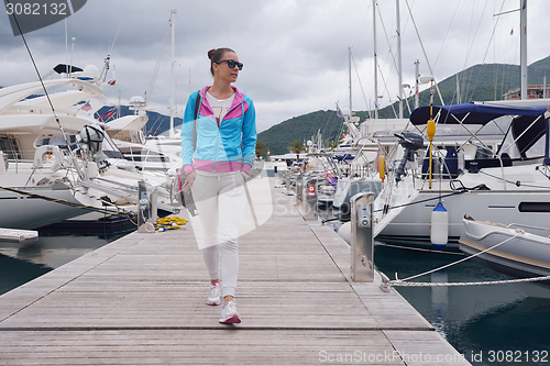 Image of relaxed young woman walking in marina