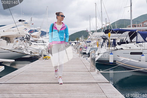 Image of relaxed young woman walking in marina