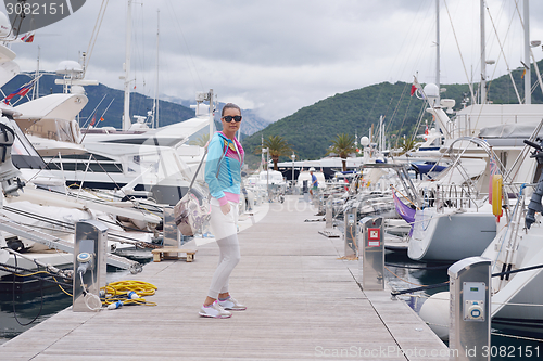 Image of relaxed young woman walking in marina