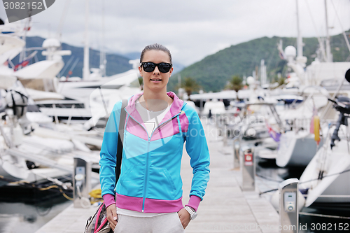 Image of relaxed young woman walking in marina