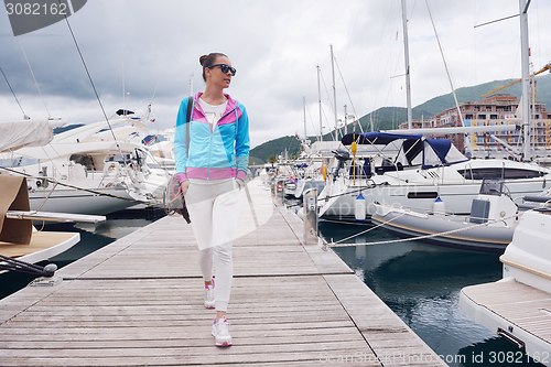 Image of relaxed young woman walking in marina