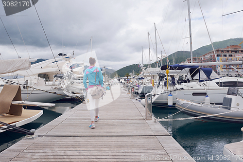 Image of relaxed young woman walking in marina