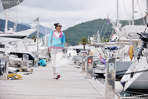 Image of relaxed young woman walking in marina