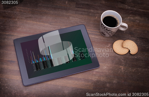 Image of Tablet touch computer gadget on wooden table, graph