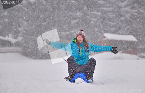 Image of girl riding sled down snow slope