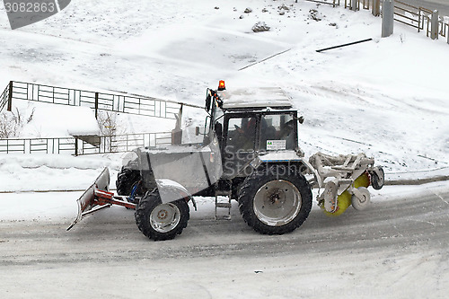 Image of The tractor sweeps snow on the road.
