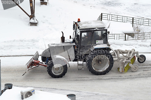 Image of The tractor sweeps snow on the road.