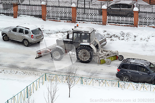 Image of The tractor sweeps snow on the road.