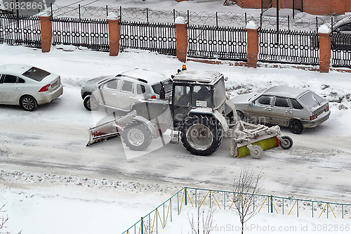 Image of The tractor sweeps snow on the road.