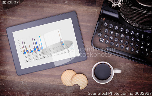 Image of Tablet touch computer gadget on wooden table, graph