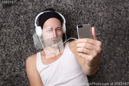 Image of Attractive man with headphones makes selfie with his mobile