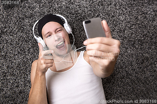 Image of Attractive man with headphones makes selfie with his mobile