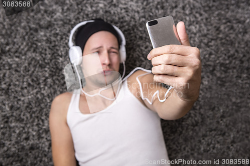 Image of Attractive man with headphones unhappy to make selfie with his m
