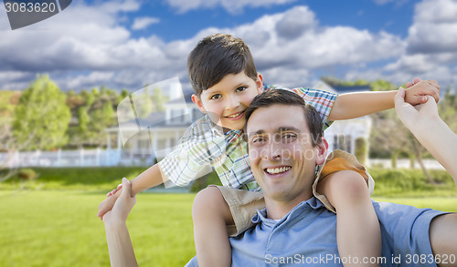 Image of Mixed Race Father and Son Piggyback in Front of House