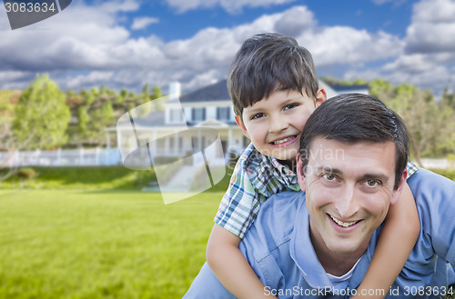 Image of Mixed Race Father and Son Piggyback in Front of House